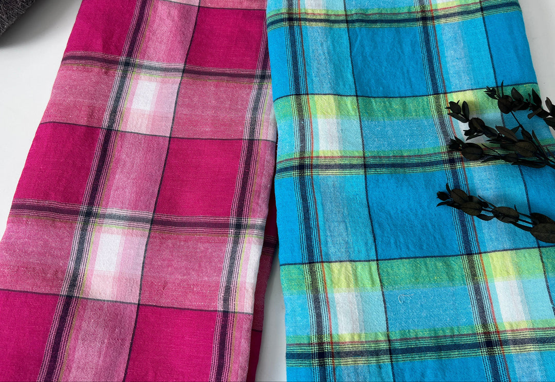 Two plaid scarves, one pink and purple, the other blue and green, on a white surface.