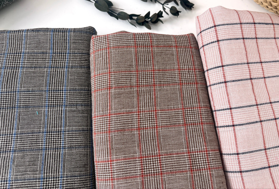 Three plaid fabrics in different patterns on a white surface with decorative elements.